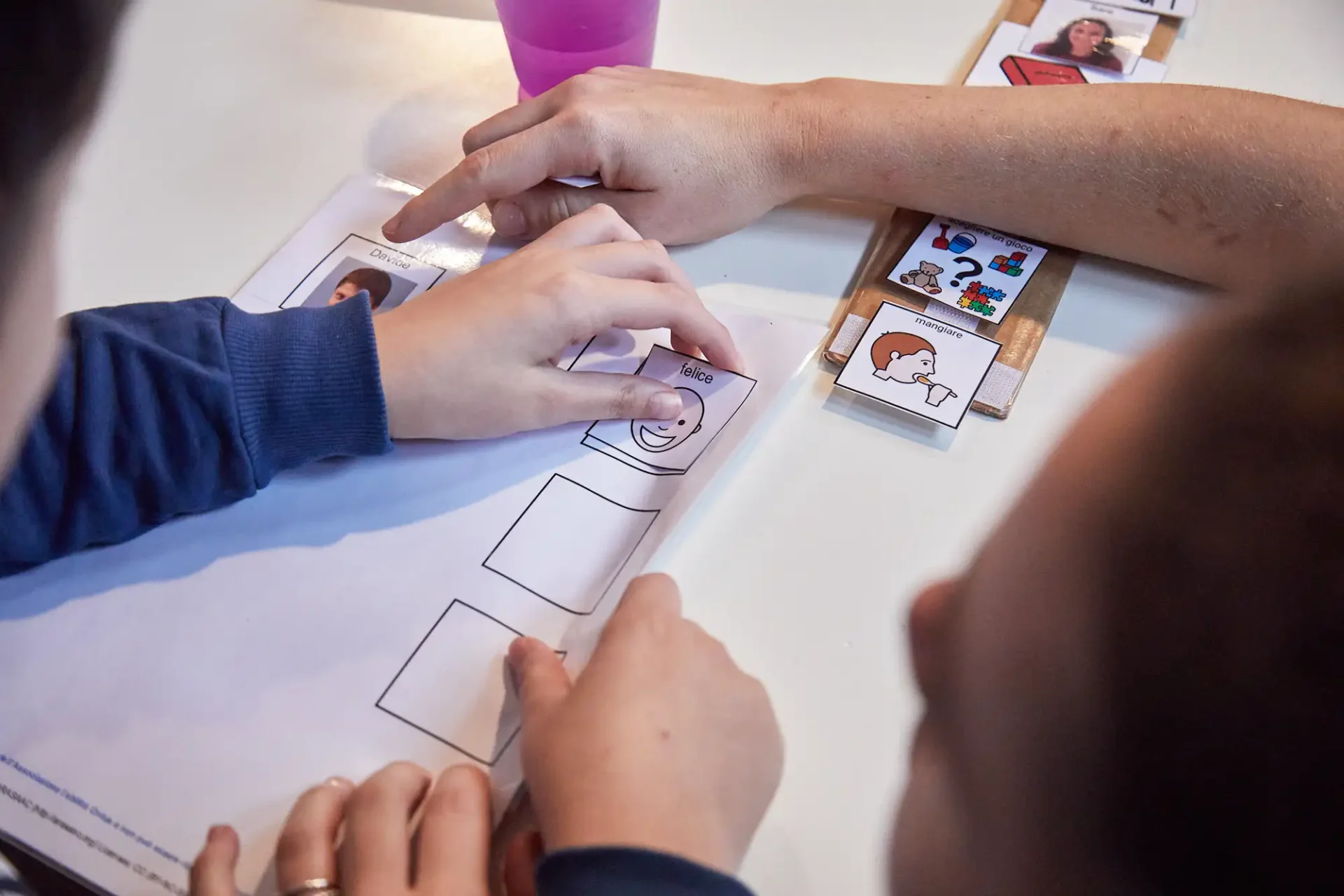 Un bambino completa una scheda con il simbolo in CAA relativo alla parola felice.