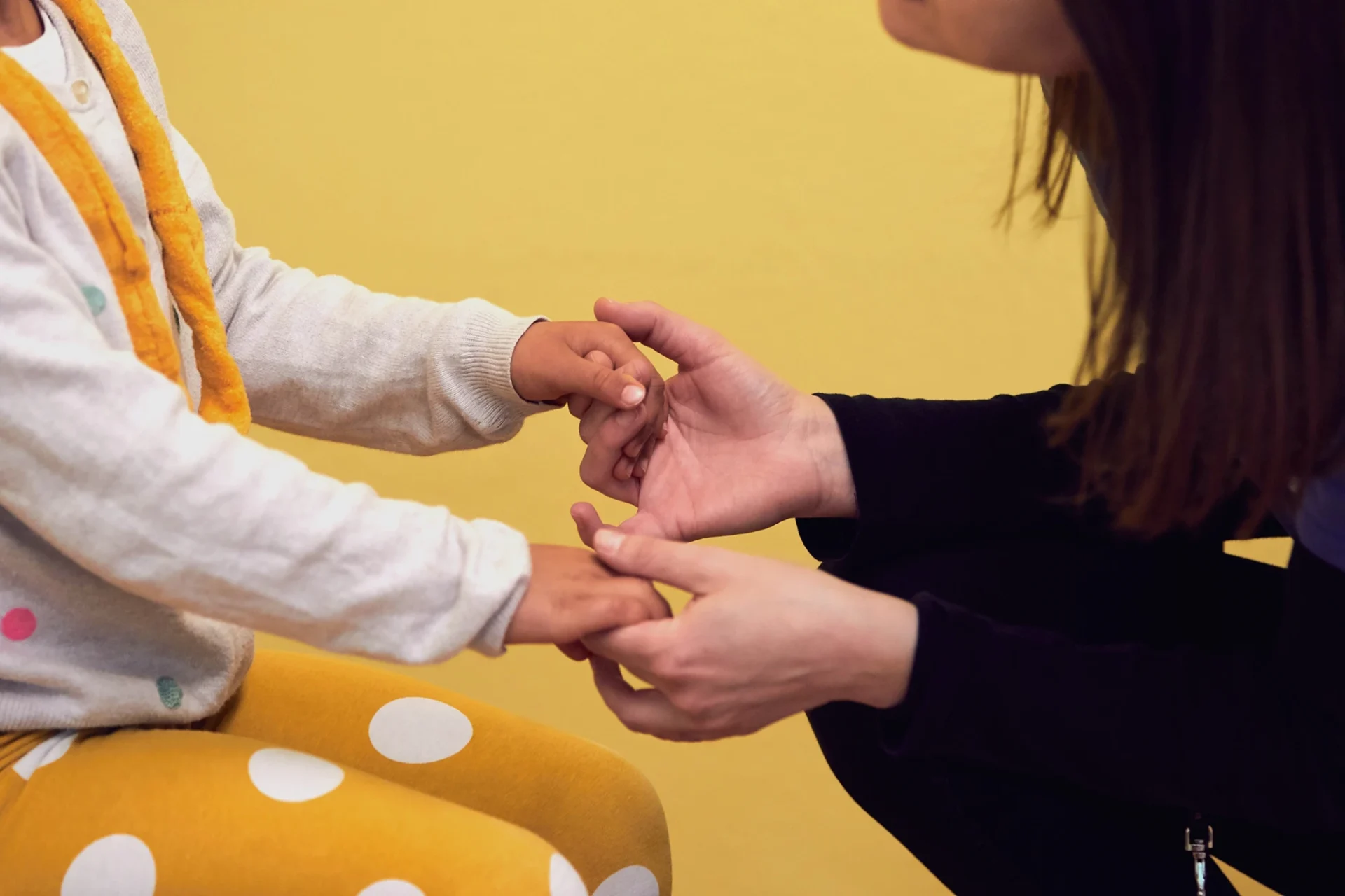 In questa foto, un'operatrice di L'abilità tiene per mano uno dei bambini.