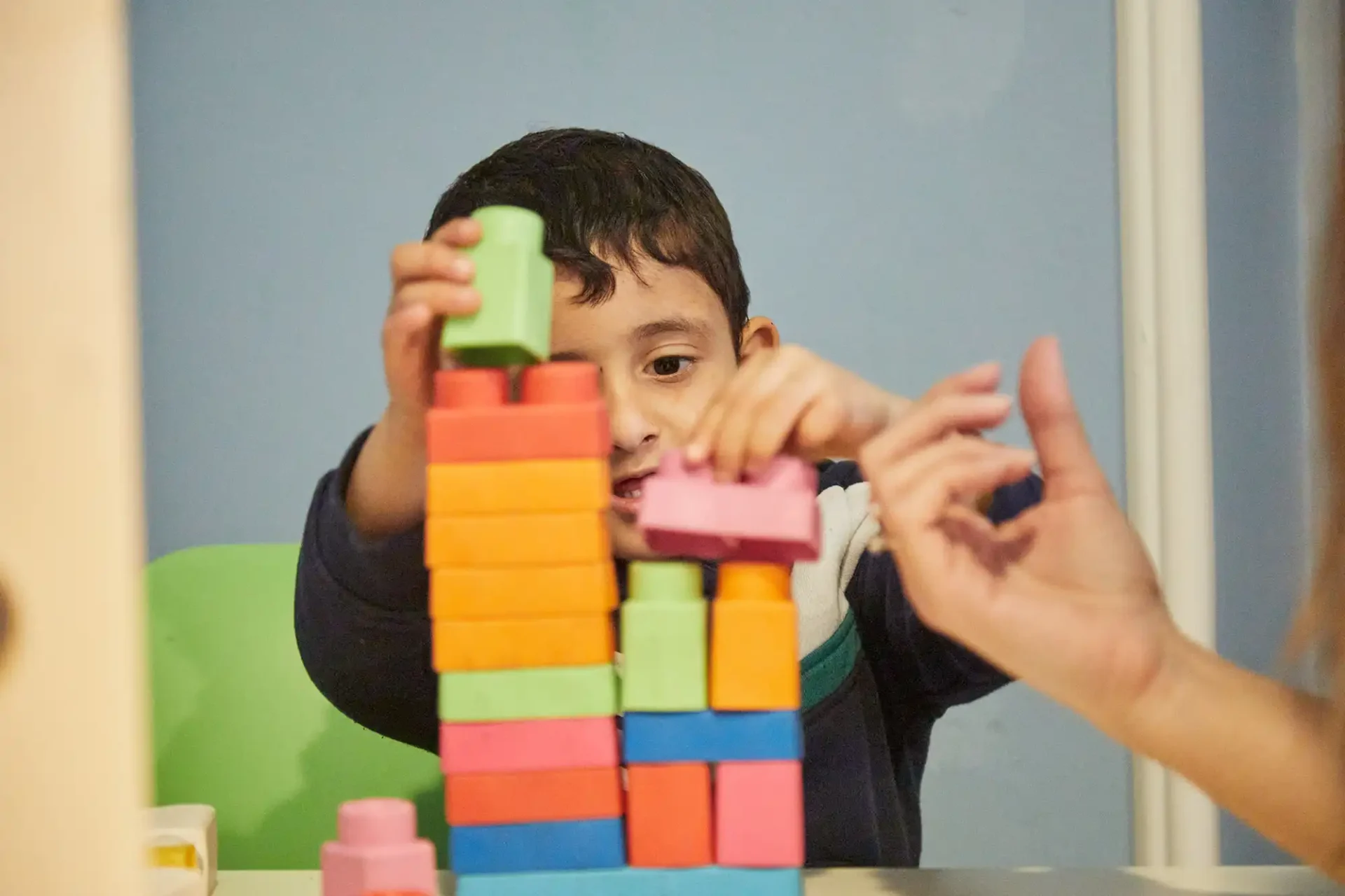 In questa foto si vede un bambino con disabilità che gioca con le costruzioni