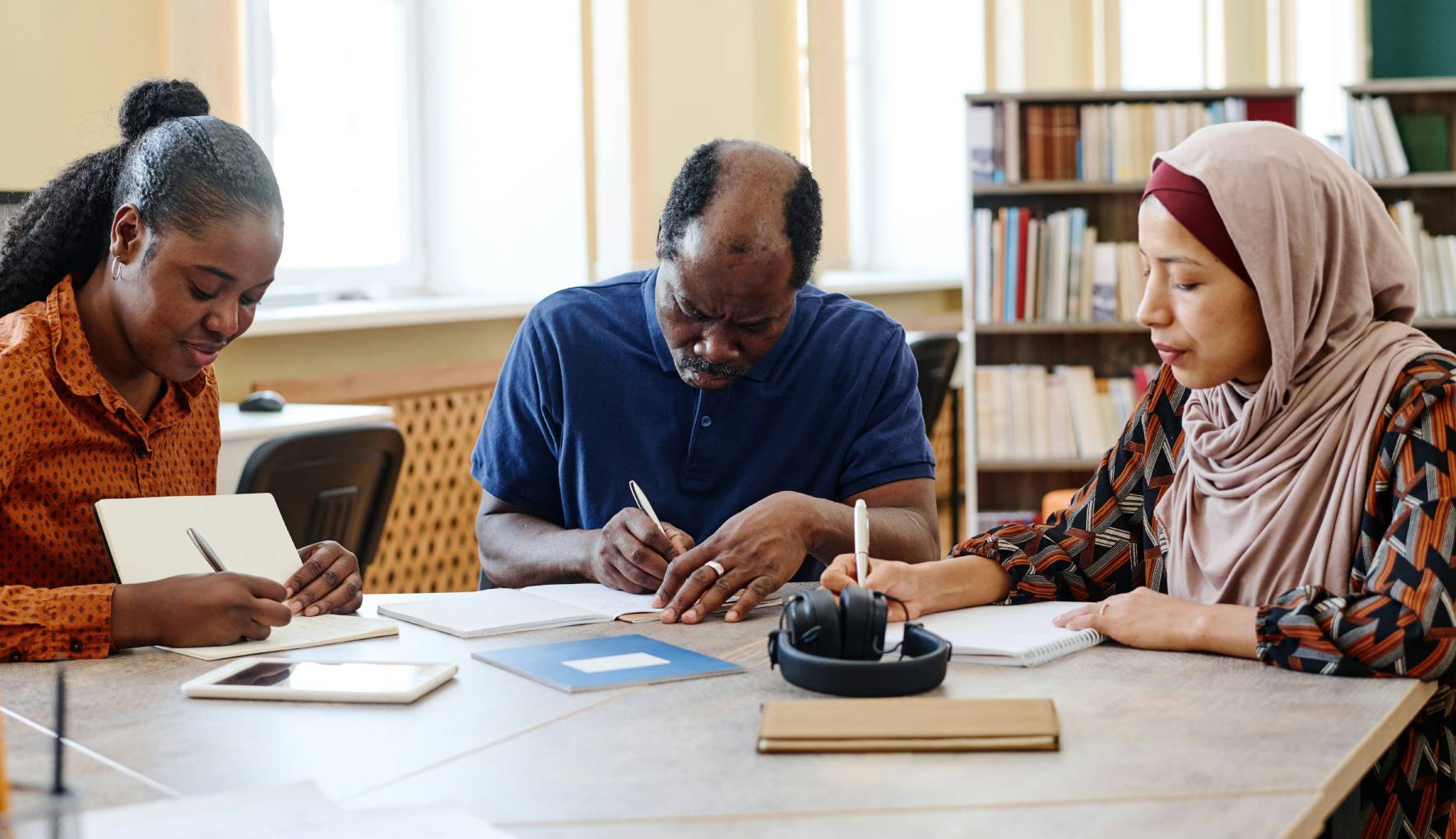 In questa foto si vede un gruppo di persone di origine straniera sedute a un tavolo