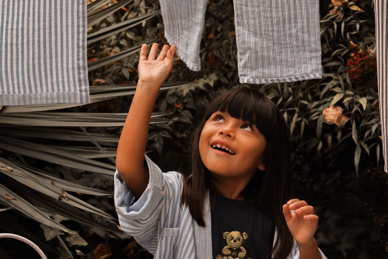 Una bambina accarezza i vestiti della collezione L'ilà
